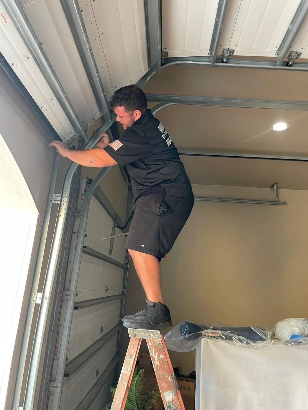 Technician on a stepladder reaching the header bracket
