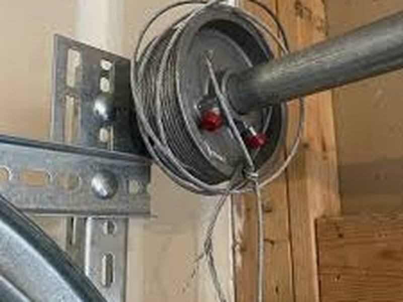 Cable drum and shaft end at the upper corner of a door