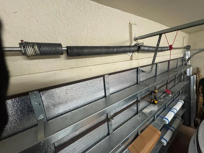 Torsion spring shaft and cables above the inside of a sectional door