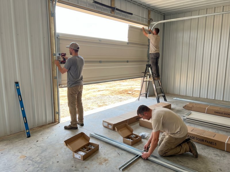 Technicians fitting a new door in an open garage frame